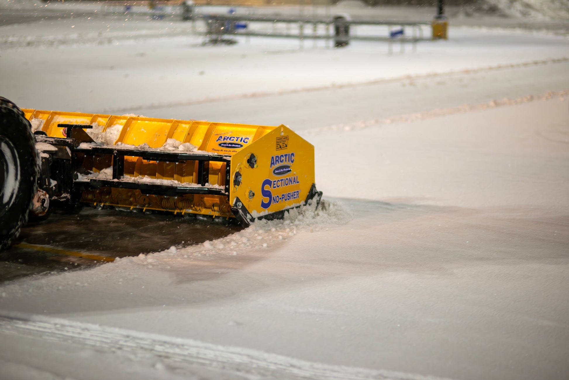 Yellow Arctic Sectional Snow Pusher on a snowy surface