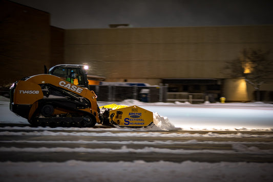 Skid steer loader with snow blade at night time
